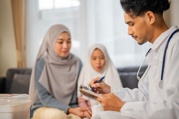 Obraz premium Isalamic Prediatician doctor give medical advise to Muslim mother and liitle girl in religious dress at home, Delivery health for kid at home concept.