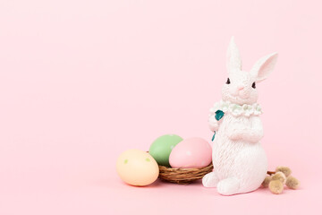 Easter bunny with painted eggs on color background