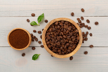 Roasted coffee beans with leaves on wooden background,top view