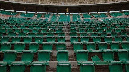 Fototapeta premium An empty stadium with numerous green plastic seats arranged in rows. 