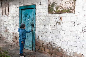 Little boy tries to open an old blue door