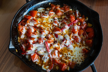 A breakfast food made of tomatoes, peppers and cheddar cheese cooked in butter in a skillet.