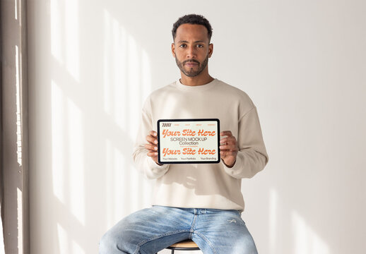 Man Holding a Tablet in Bright Interior Setting. PSD horizontal screen mockup