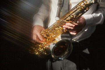 Close up shot on brass saxophone in hands of male musician playing jazz music on stage under bright...