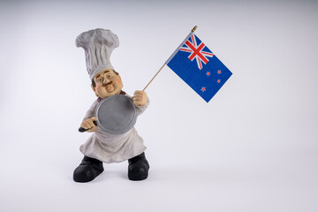Chef figurine  with area for your message on a white background. Chef holding national flag of New Zealand