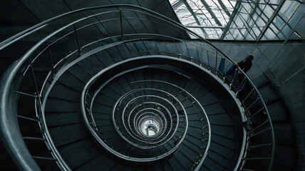 A sleek, modern spiral staircase with dark steps and metallic handrails. 
