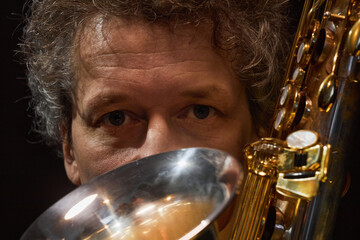 Close up portrait of professional middle aged male musician intently looking at camera while hiding...
