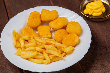 French fries and golden nuggets with cheese sauce on a plate
