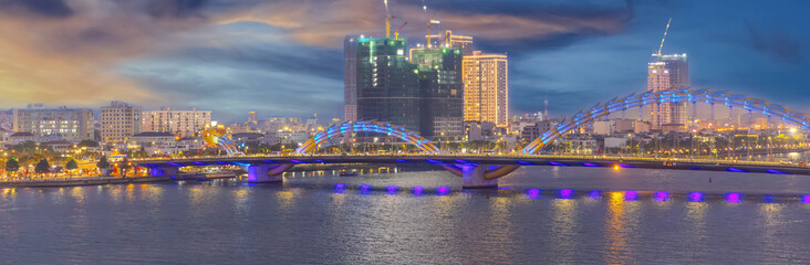 Naklejka premium 29 March 2025 Fire Breathing Dragon Bridge at Da Nang over a river, wonderful colours of the Sky at night and river in Da Nang Vietnam. thousands of spectators line up on Saturday and Sunday night 