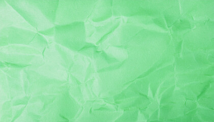 Crumpled green recycled paper texture with natural wrinkles and creases. Minimalist background.