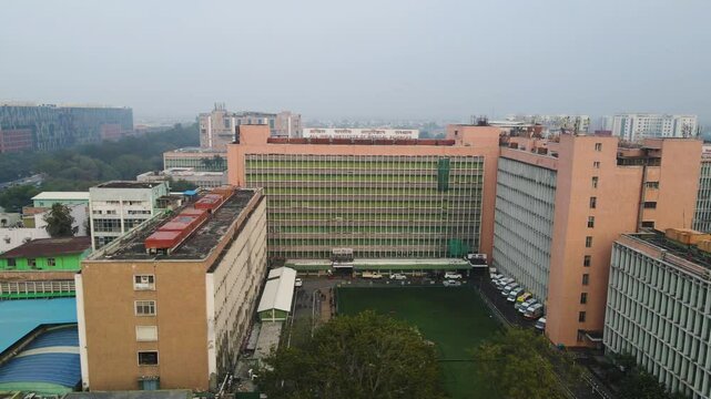 Aerial drone shot capturing the daily activity around AIIMS, with busy roads, hospital buildings, and medical staff in motion.