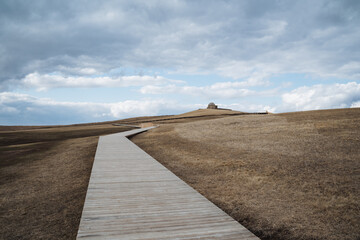 A wellconstructed concrete walkway runs gently through a dry grassy field, providing a smooth and easy path across the landscape, stretching far into the distant horizon