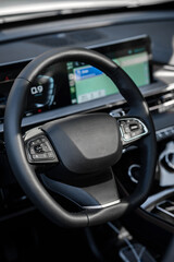 Close-up on steering wheel with integrated buttons and crisp digital dashboard, illuminated by natural daylight, digital dashboard displaying navigation and settings