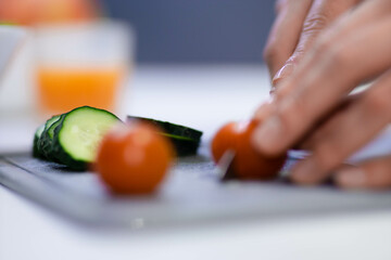 Close up shot of female hands preparing breakfast in kitchen using knife. Woman slicing fresh...