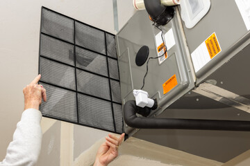 Replacing dirty central air conditioning  air filter.  HVAC repair technician performing maintenance on home indoor heating and cooling system. Air duct ventilation system maintenance for clean air. 
