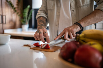 Chef cutting strawberries on wooden board in modern kitchen