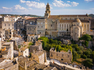 Scenic view of Gravina in Puglia, Italy, showcasing historic stone architecture, the iconic Roman bridge over the ravine, and the picturesque old town under a clear blue sky.