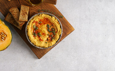 Pumpkin hummus with olive oil , chickpeas and flat bread on wooden board, copy space, top view