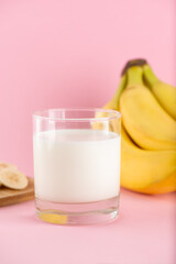 Banana milk in a glass on a pink background. Traditional Korean drink. Vertical orientation.