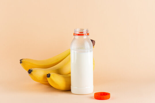 Sweet banana milk in a bottle with bananas on a beige background. Traditional Korean drink.