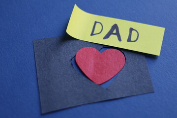 Una toma de cerca de la palabra padre acompañada de un corazón rojo  en un fondo azul para ser...