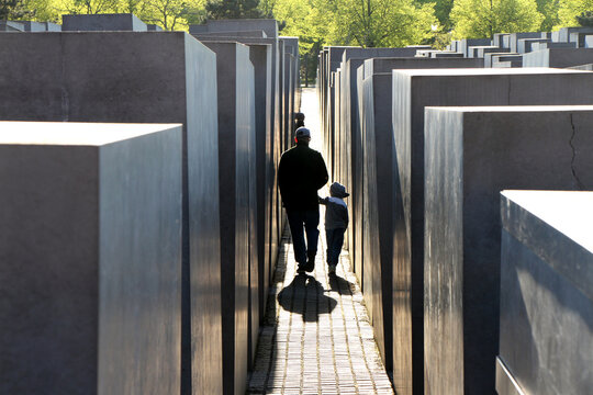 Father and Child Walking Through the Holocaust Memorial in Berlin at Sunset