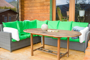 Wooden terrace with green cushions and a round wooden table