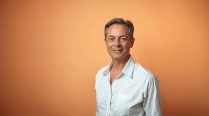 Smiling Man in White Shirt Posing Against Warm Orange Background Portrait