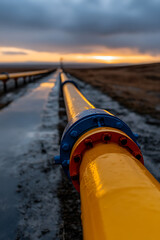 Industrial pipeline stretches across an open landscape at sunset, highlighting engineering and infrastructure in a natural setting. Focus is on connectivity.