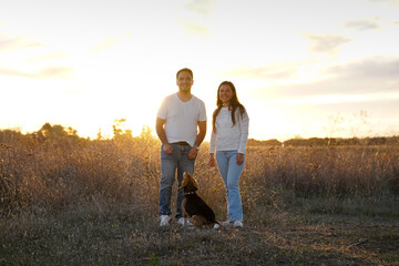 A Loving Couple Latin American and Their Adorable Dog Beagle Enjoying a Beautiful Sunset in a Serene Field