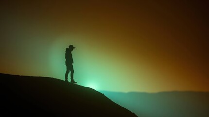 Silhouette of a Person Standing on a Hill Against a Foggy Background