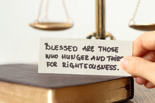 Christian blessing for righteousness, handwritten quote with holy bible book and balance scale in the background. Close-up. Justice and obedience to God Jesus Christ, biblical concept.