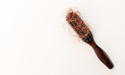 Hair loss, red hair fall everyday serious problem, hairbrush with fall red hair on beige background
