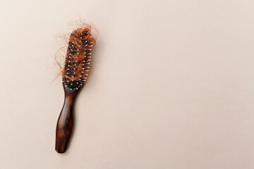 Hairbrush with fall red hair from scalp after brushing, worry about balding. Health care, beauty treatment, hair loss problem. Hairbrush on beige background