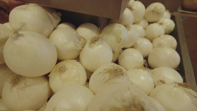 Fresh white onions neatly arranged on a grocery store shelf, showcasing their smooth, pale skin and firm texture in a well-lit retail environment