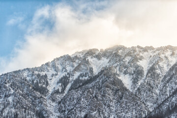 Snow covered Gore mountain range in morning sunrise clouds near Vail and blue sky with jagged peaks and trees