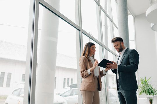 Car dealers discussing a contract with a tablet in a showroom