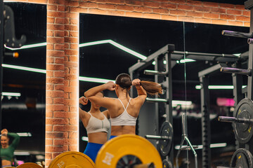 Young woman tying hair in modern gym getting ready for workout