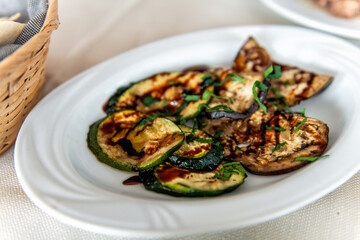 Grilled eggplant zucchini slices courgette in balsamic vinegar sauce, basil leaf herb as Sardinian traditional dish in Sardinia macro closeup