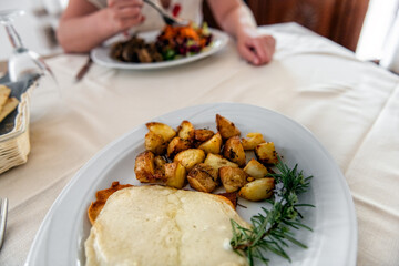 Sardinian roasted goat cheese and potatoes on restaurant plate dining dinner local cuisine for Caprino del Supramonte in Sardinia, Italy