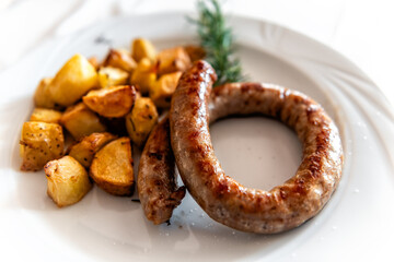 Sardinian Salsiccia arrosto pork sausage with roasted potatoes, rosemary as traditional meat vegetable dish meal plate in Sardinia Italy macro closeup