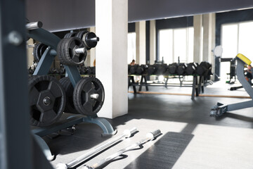 Different weight plates on rack and other equipment in gym. Space for text