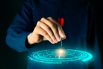 Woman aiming at virtual dartboard with dart on black background, closeup. Targeting concept