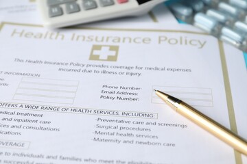 Health insurance policy, pen, calculator and pills, closeup