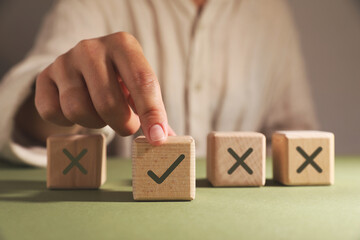 Approved. Woman choosing cube with check mark among other ones with crosses at table, closeup