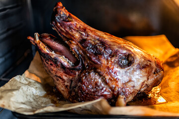 Pig pork head cooked roasted baked animal meat ready to eat on baking tray sheet in kitchen home, inside oven roasting