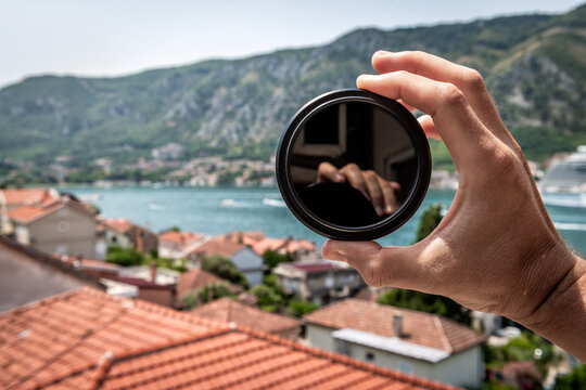 Neutral density nd filter for camera lens person hand holding macro closeup outside in Kotor, Montenegro with landscape nature view
