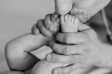 Dad tenderly kisses his newborn son's feet. fathers day