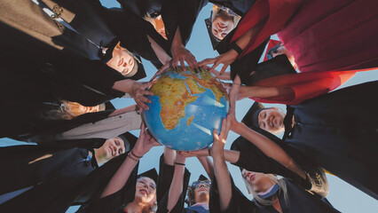 Graduates in cap and gown holding globe, representing international education and future professional prospects