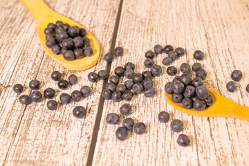 Ripe fresh wild blueberries in large wooden spoon on old wooden board.